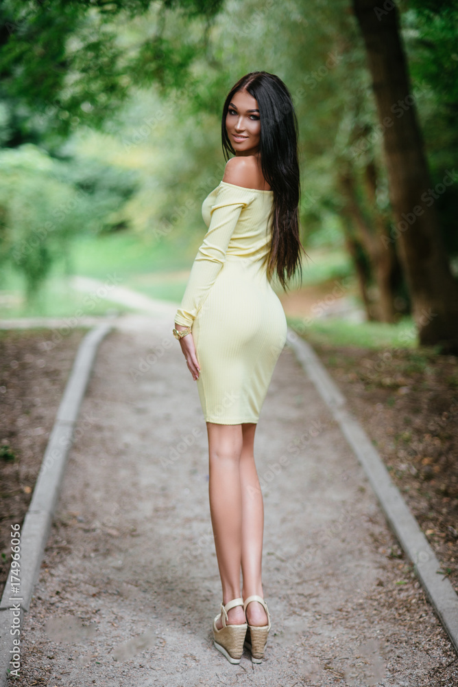 young beautiful brunette woman posing in yellow elegance dress at green summer park young beautiful brunette woman posing in yellow elegance dress at green summer park
