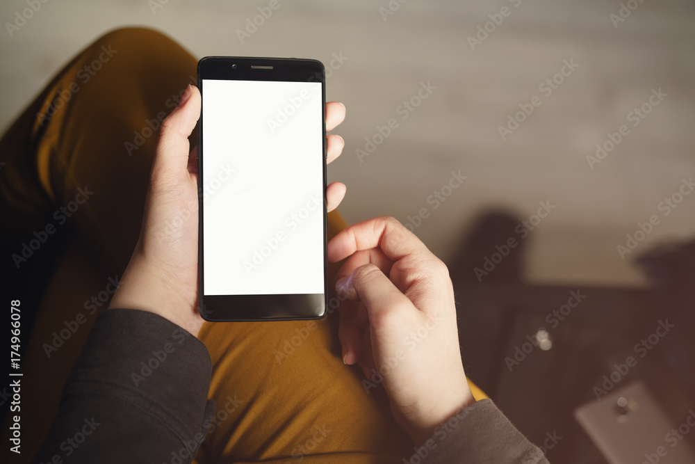 pov view young female hands holding smartphone with white screen while sitting indoors - obrazy, fototapety, plakaty 
