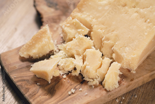 pieces of hard parmesan cheese on olive board from above