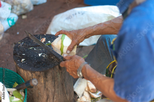 Old men are peeling coconuts for sale.