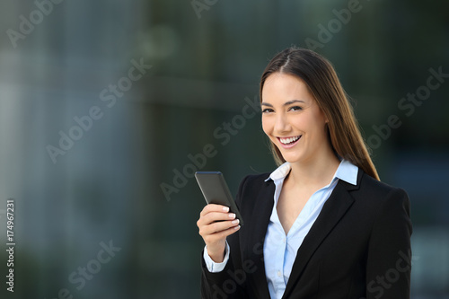 Happy executive using phone and looking at camera