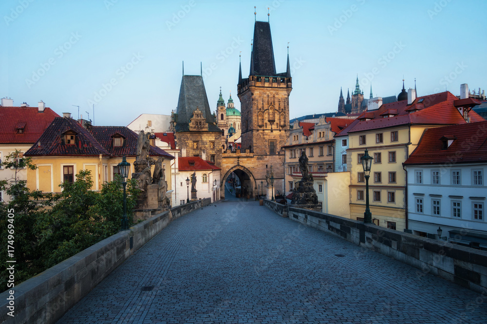 Charles Bridge in Prague in the early morning. View of Malostranska Tower and Judithin Tower. In the background on the mountain you can see Prague Castle.