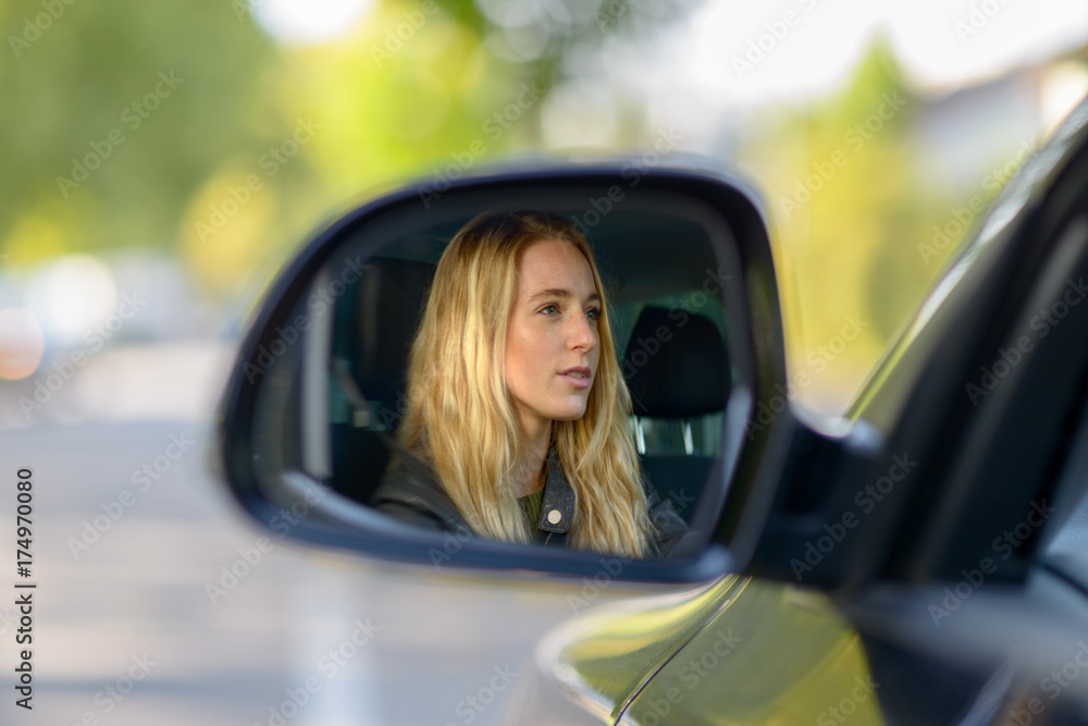 Reflection of blonde woman in car wing mirror