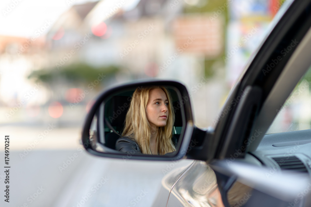 Reflection of blonde woman in car wing mirror