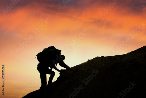 A silhouette of man climbing on rock  mountain at sunset Despite the many obstacles we will keep going highest goals expected as until it succeeds.