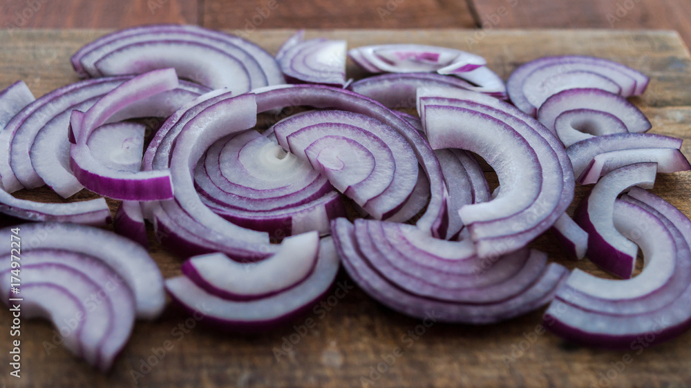 Food preparation, cooking concept: sliced fresh red onions on rustic wooden background