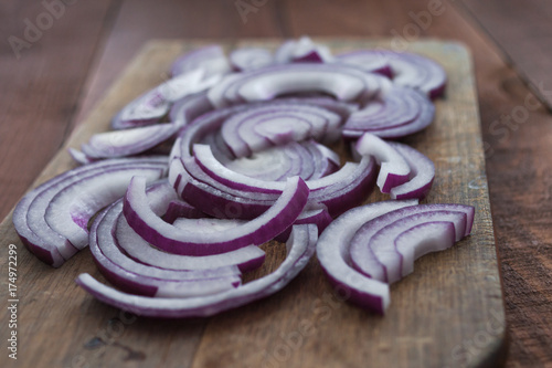 Food preparation, cooking concept: sliced fresh red onions on rustic wooden background photo