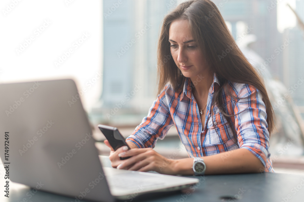 Attractive young woman reading a text message on her cell phone. Girl sitting outdoors using smartphone Attractive young woman reading a text message on her cell phone. Girl sitting outdoors using smartphone