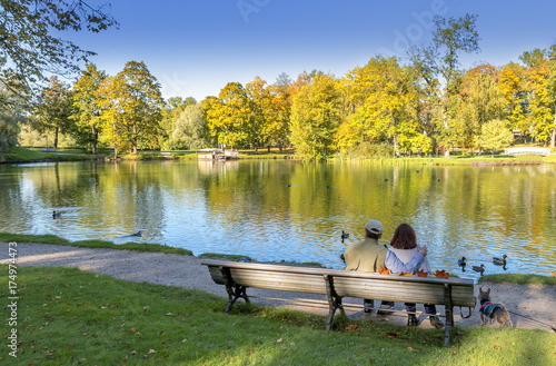 Happy couple of seniors are resting on the wooden bench in a city public park