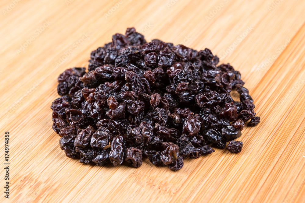 Black organic zante currants on a wood background Black organic zante currants on a wood background