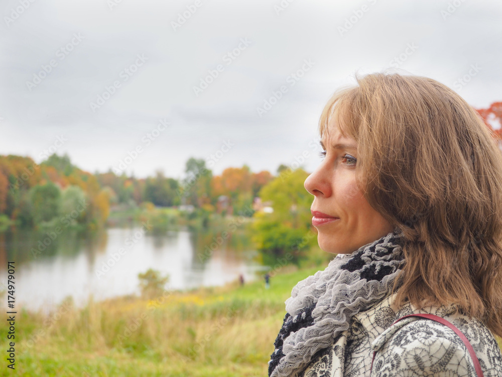 Blonde middle-aged woman in the autumn on the background of nature.
