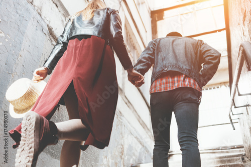 Young couple in love holding hands and climbing stairs on a sunny day.