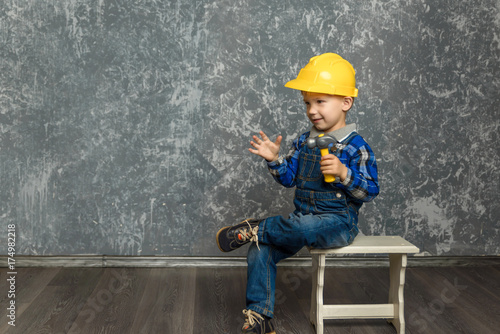 the boy in yellow hard hat holding a hammer
