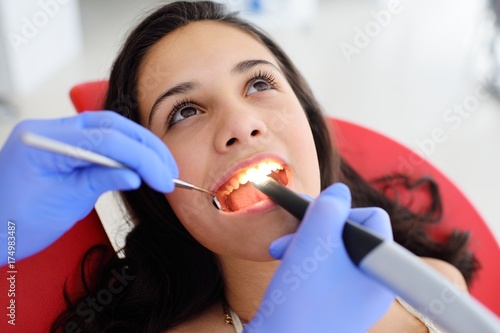 Baby girl sitting in red dental chair on examination at dentist