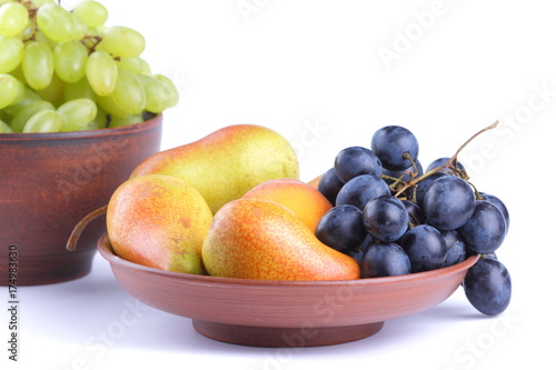 Yellow pears  green and blue grapes in a clay plate on a white background