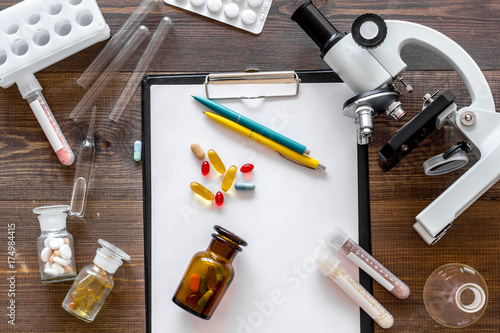 Laboratory test. Microscope, pills, test tube on wooden background top view
