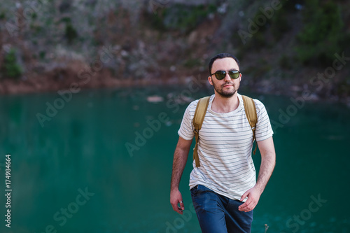 Bearded man model poses alongside a Green water Lake.