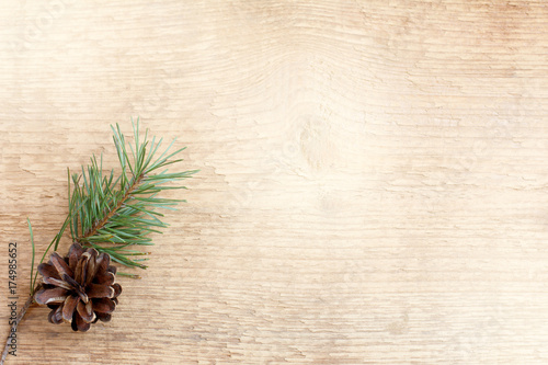 decoration for winter holidays/ pine twig and cone on a light wooden surface top view 