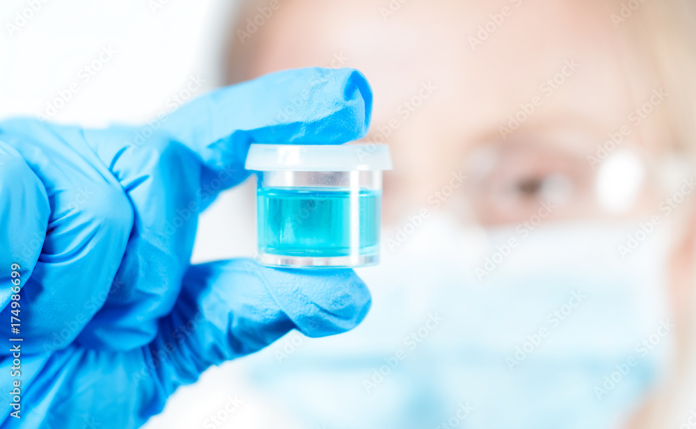 Chemist in protective eyeglasses holding test tube with reagent in lab Chemist in protective eyeglasses holding test tube with reagent in lab
