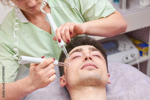 Microcurrent therapy, male face. Cosmetologist working with customer.