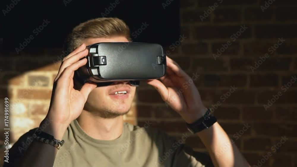Handsome caucasian man enjoying a virtual reality helm, in front of the brick wall, slow motion Handsome caucasian man enjoying a virtual reality helm, in front of the brick wall, slow motion