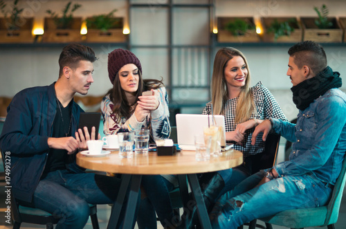 Group of young people sitting in a coffee shop having fun