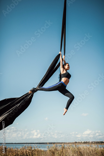 Elegance young beautiful woman dance with aerial silk on a sky background. Fly yoga sport  photo