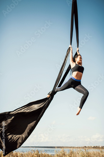 Elegance young beautiful woman dance with aerial silk on a sky background. Fly yoga sport 