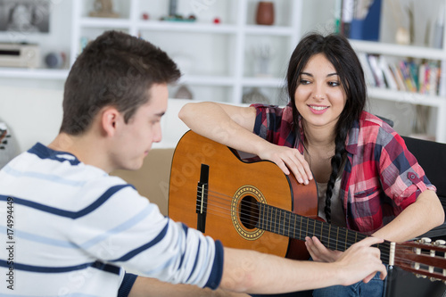teen boy listening to the boy playing the guitar
