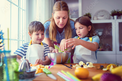 Cute kids with mother preparing a healthy fruit snack in kitchen 