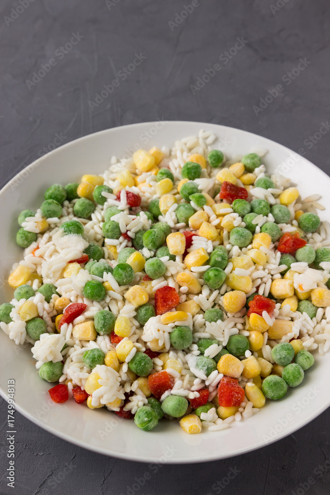 Frozen vegetables: corn, peas, tomatoes, carrots with rice on a plate. Frozen vegetables: corn, peas, tomatoes, carrots with rice on a plate.