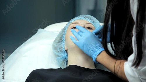 In the beauty salon the doctor-cosmetologist prepares the girl to the procedure for lip augmentation photo