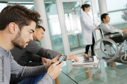 man use smart phone while waiting at a clinic