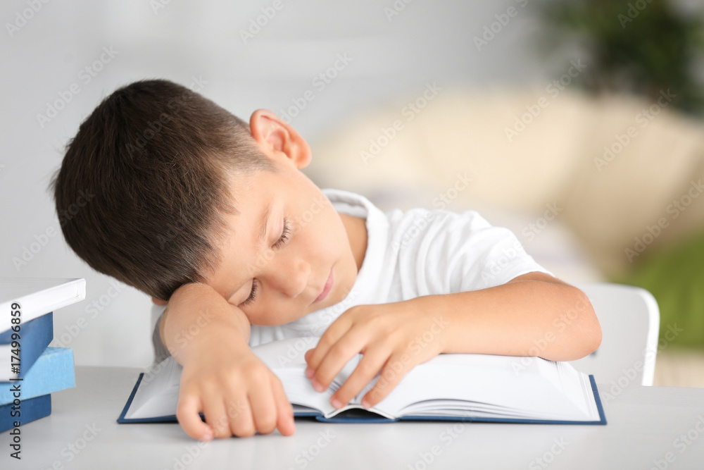 Cute little boy sleeping while sitting at table with book Cute little boy sleeping while sitting at table with book