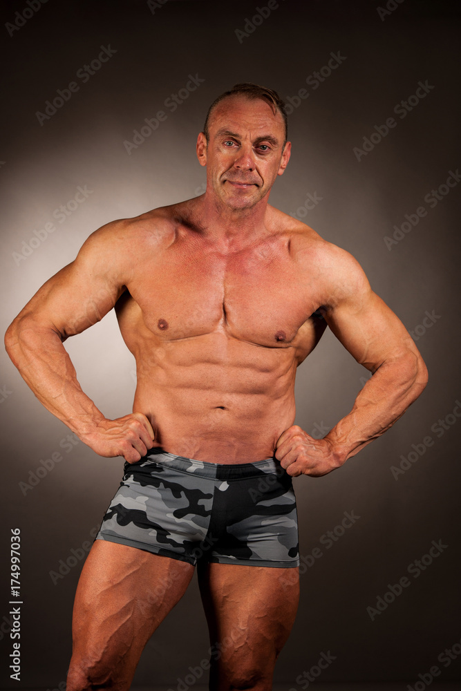 bodybuilder pose in studio over dark background