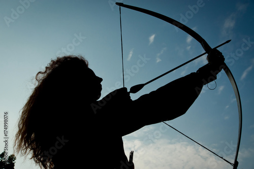 Red haired girl shoots from the bow