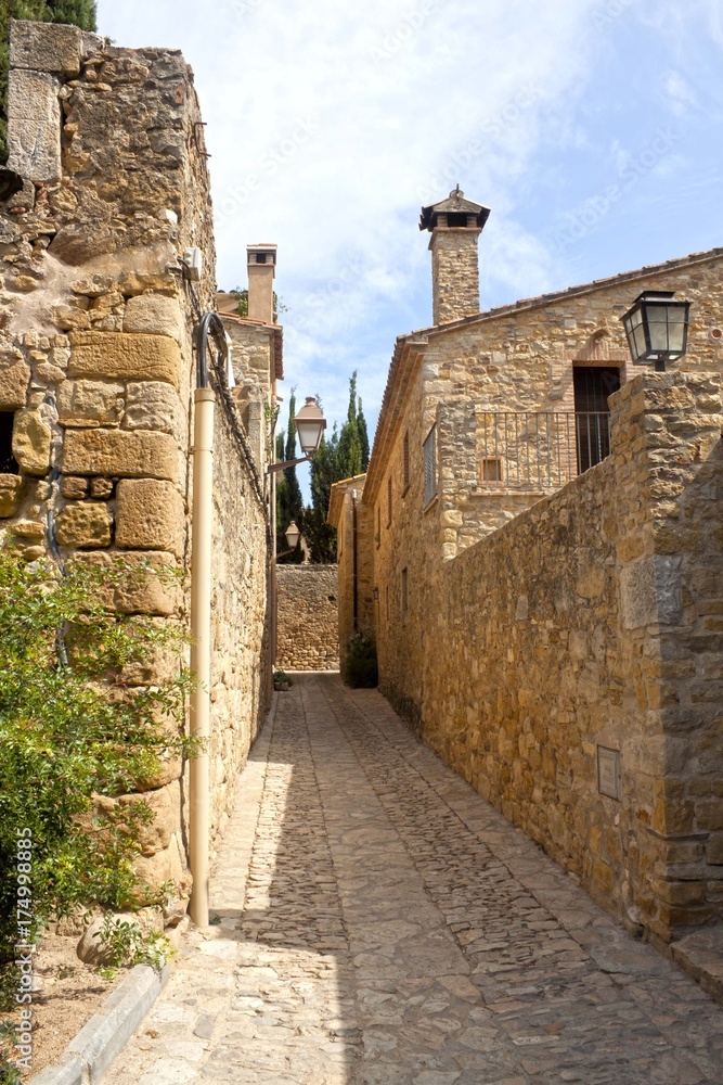 Narrow street, stone pavement and a clear sky in Peratallada, Spain