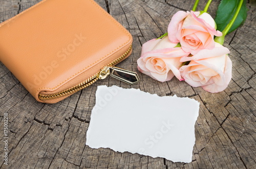 Wallet with flowers and paper on wooden background. photo