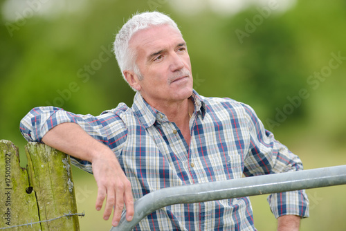 outdoorsman leaning on fence photo