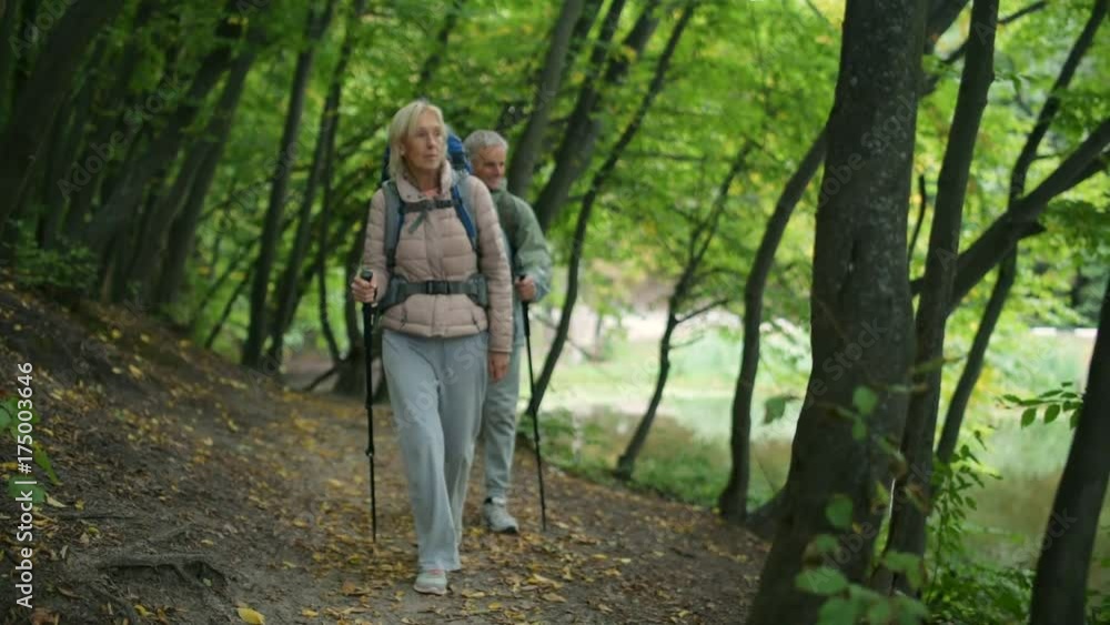 Positive couple of tourists walkign in the wood Positive couple of tourists walkign in the wood