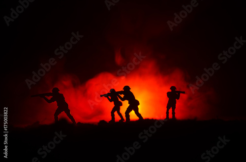 Military silhouettes of soldiers against the backdrop of dark foggy sky. Battle scene with explosion and burning clouds behind fighing soldiers. Toy decoration