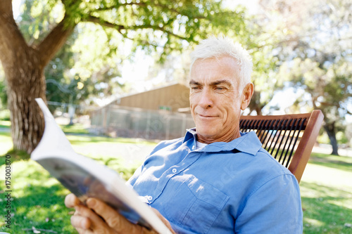 Senior man sittingin park while reading book photo