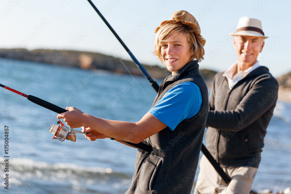 Obraz premium Senior man fishing with his grandson