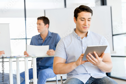 Young handsome businessman using his touchpad sitting in office