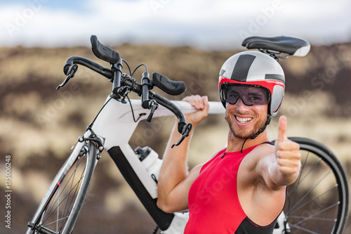 Obraz na płótnie Triathlon biking - male triathlete cycling giving thumbs up success hand sign cheering happy excited at camera