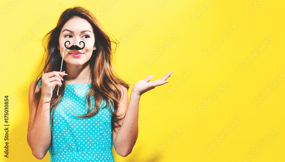 Φωτογραφία Young woman holding paper party sticks on a yellow background