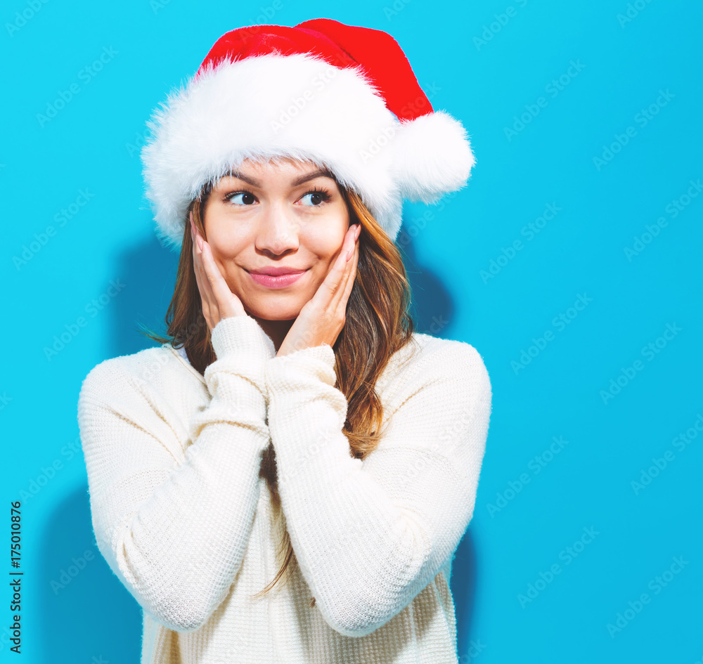Happy young woman with Santa hat on a blue background Happy young woman with Santa hat on a blue background