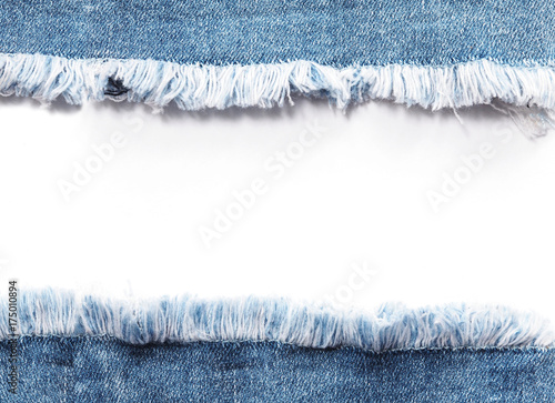 Fototapeta Edge frame of blue denim jeans ripped over white background.