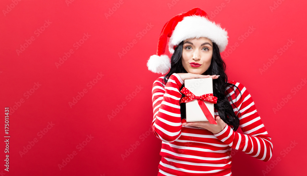 Young woman with Santa hat holding a Christmas present Young woman with Santa hat holding a Christmas present