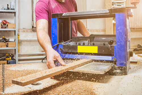 man scouring a wooden board on an thicknessing machine photo